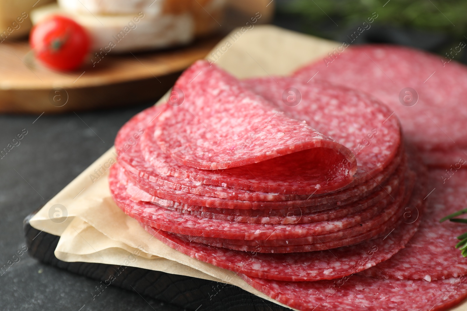 Slices of tasty smoked sausage on black table, closeup Photo of Slices of tasty smoked sausage on black table, closeup
