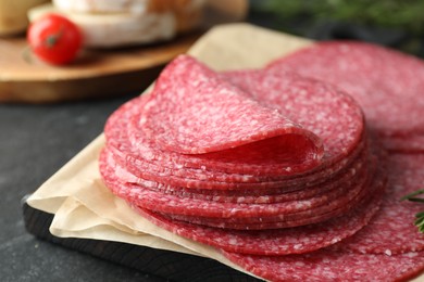 Photo of Slices of tasty smoked sausage on black table, closeup