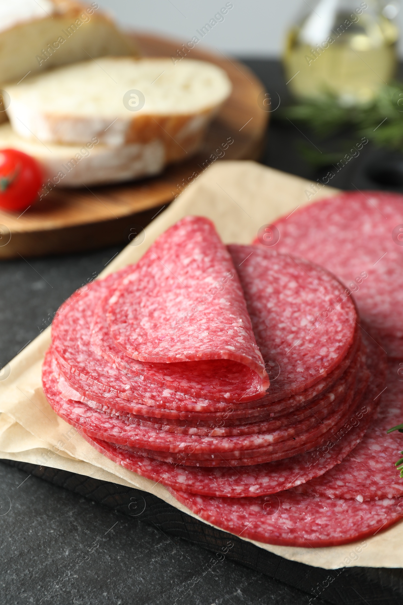 Slices of tasty smoked sausage on black table, closeup Photo of Slices of tasty smoked sausage on black table, closeup
