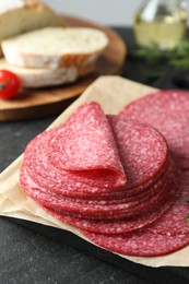 Photo of Slices of tasty smoked sausage on black table, closeup