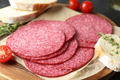 Photo of Slices of tasty smoked sausage, tomatoes, thyme and bread on table, closeup