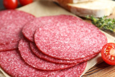 Photo of Slices of tasty smoked sausage, tomato, thyme and bread on table, closeup