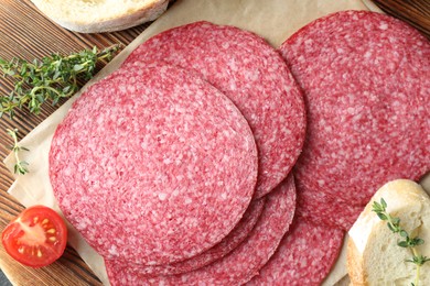 Photo of Slices of tasty smoked sausage, tomato, thyme and bread on table, top view