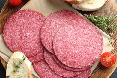 Photo of Slices of tasty smoked sausage, tomato, thyme and bread on table, top view