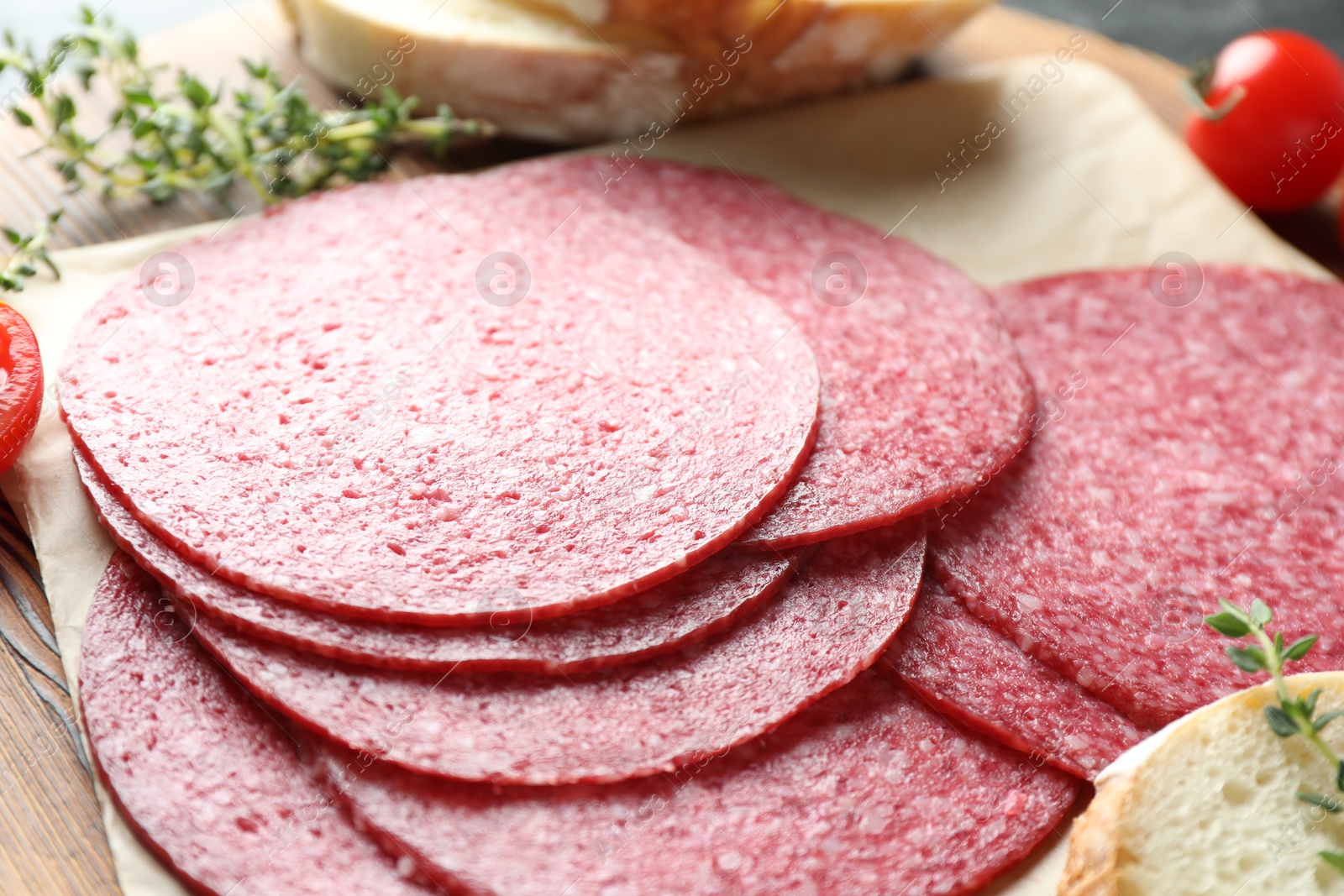 Photo of Slices of tasty smoked sausage, tomato, thyme and bread on table, closeup