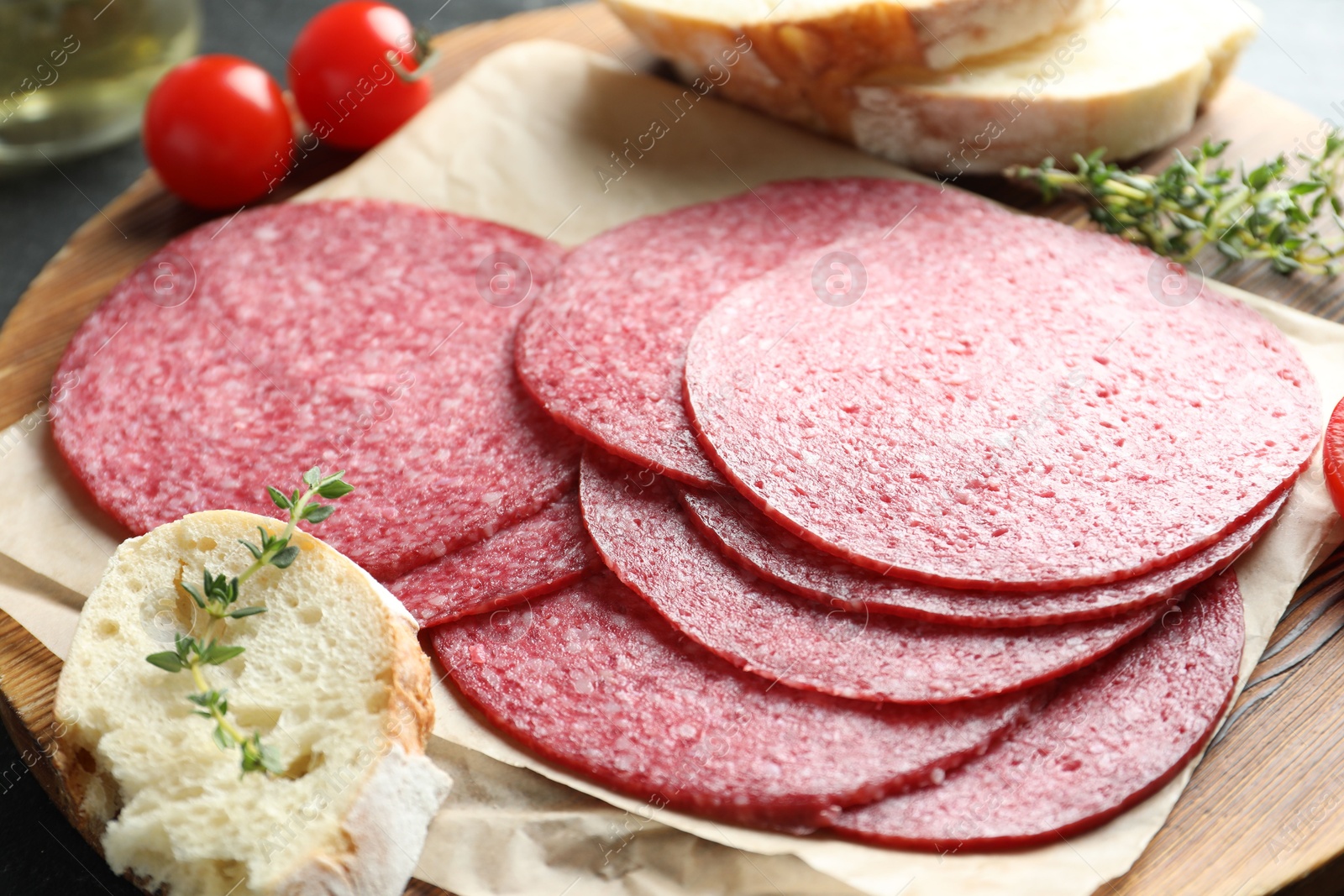 Slices of tasty smoked sausage, bread, tomatoes and thyme on table, closeup Photo of Slices of tasty smoked sausage, bread, tomatoes and thyme on table, closeup