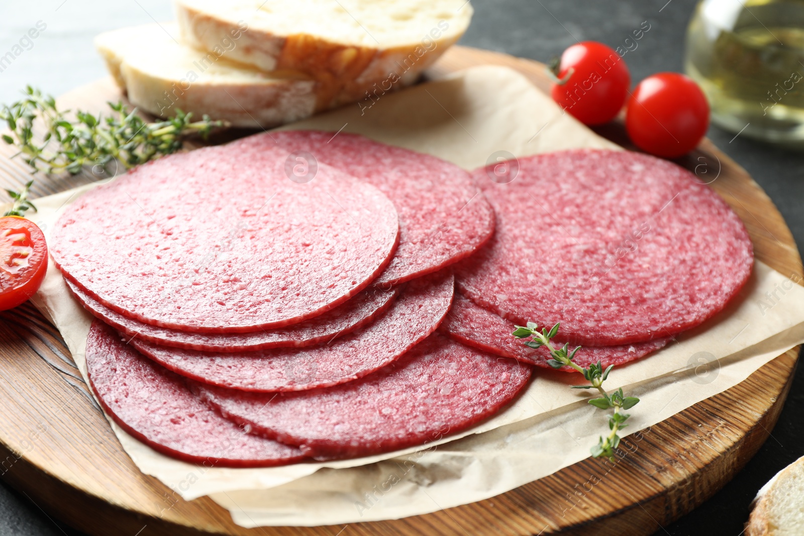 Slices of tasty smoked sausage, bread, tomatoes and thyme on table, closeup Photo of Slices of tasty smoked sausage, bread, tomatoes and thyme on table, closeup