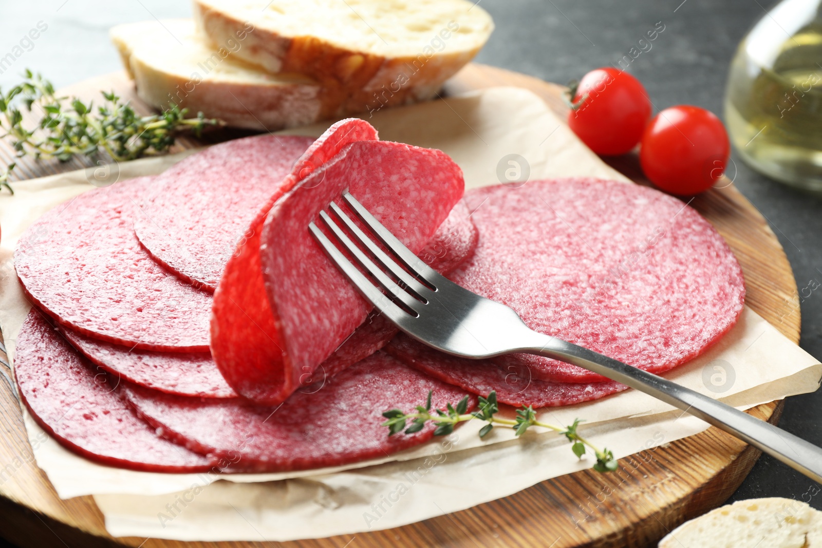 Slices of tasty smoked sausage, bread, tomatoes, thyme and fork on table, closeup Photo of Slices of tasty smoked sausage, bread, tomatoes, thyme and fork on table, closeup