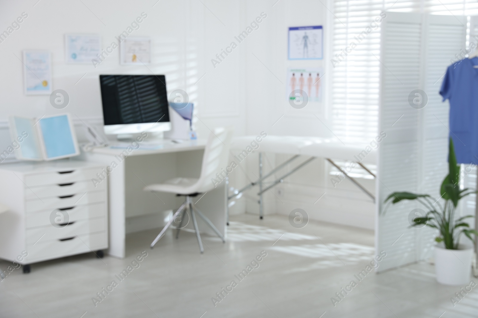 Doctor's workplace with modern computer and examination table in medical office, blurred view Photo of Doctor's workplace with modern computer and examination table in medical office, blurred view