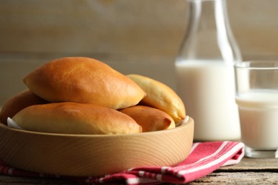 Photo of Tasty baked patties and milk on wooden table, closeup