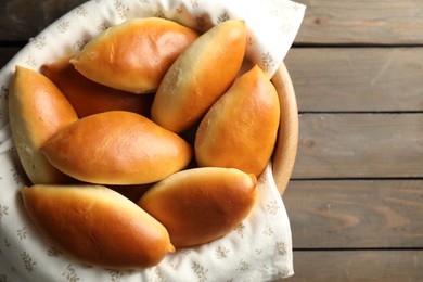 Photo of Tasty baked patties in bowl on wooden table, top view. Space for text
