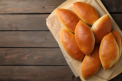 Photo of Tasty baked patties on wooden table, top view. Space for text