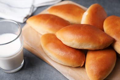 Photo of Tasty baked patties and milk on light grey table, closeup