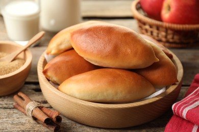 Photo of Tasty baked patties and ingredients on wooden table, closeup