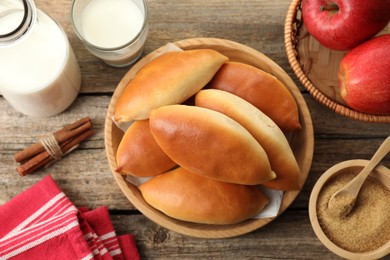 Photo of Tasty baked patties and ingredients on wooden table, flat lay