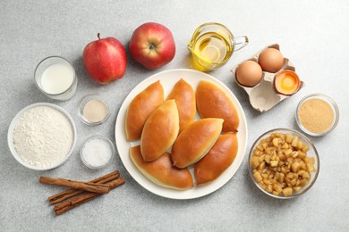 Photo of Tasty baked patties and ingredients on light grey table, flat lay
