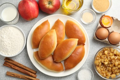 Photo of Tasty baked patties and ingredients on light grey table, flat lay