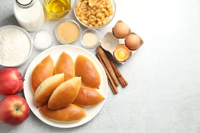 Photo of Tasty baked patties and ingredients on light grey table, flat lay. Space for text