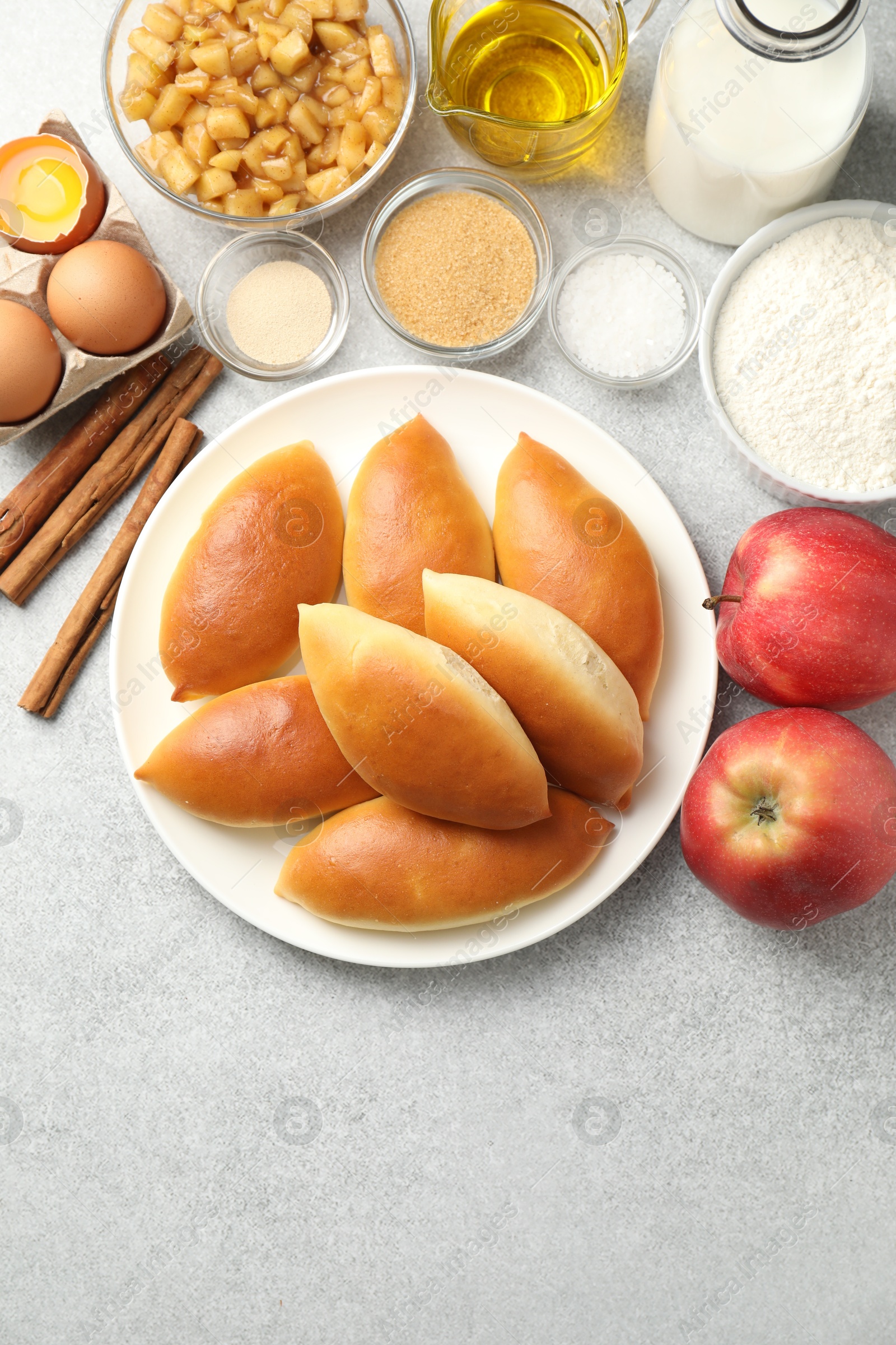 Tasty baked patties and ingredients on light grey table, flat lay. Space for text Photo of Tasty baked patties and ingredients on light grey table, flat lay. Space for text