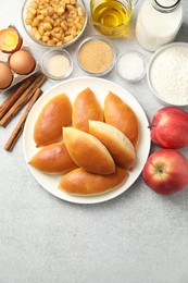 Photo of Tasty baked patties and ingredients on light grey table, flat lay. Space for text