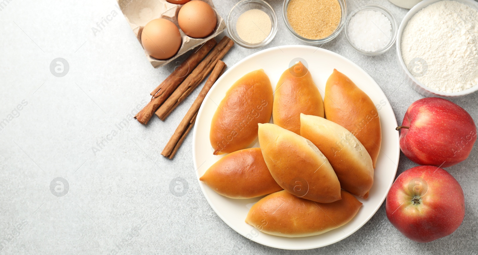 Tasty baked patties and ingredients on light grey table, flat lay. Space for text Photo of Tasty baked patties and ingredients on light grey table, flat lay. Space for text