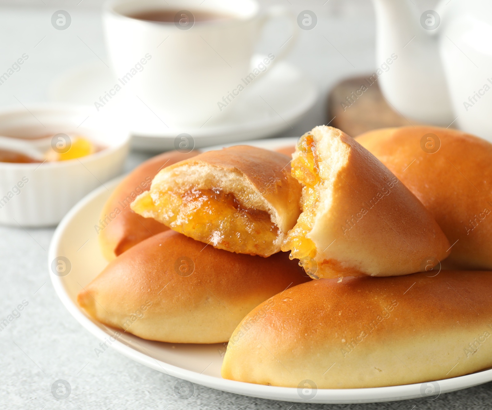 Tasty baked patties with orange jam on light grey table, closeup Photo of Tasty baked patties with orange jam on light grey table, closeup