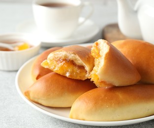 Photo of Tasty baked patties with orange jam on light grey table, closeup