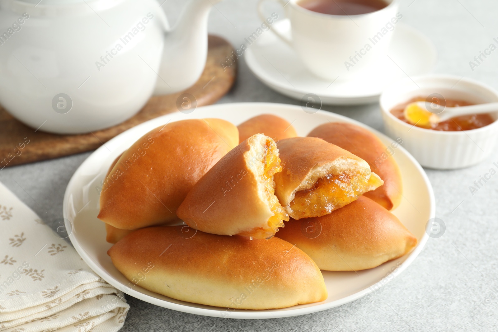 Tasty baked patties with orange jam on light grey table, closeup Photo of Tasty baked patties with orange jam on light grey table, closeup