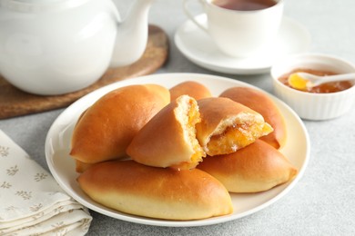 Photo of Tasty baked patties with orange jam on light grey table, closeup