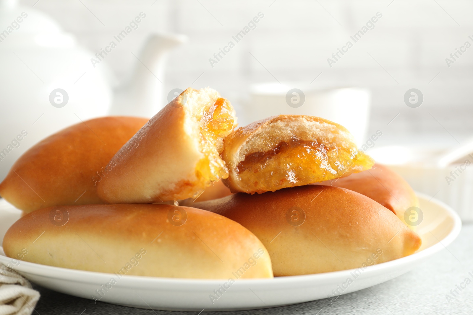 Tasty baked patties with orange jam on light grey table, closeup Photo of Tasty baked patties with orange jam on light grey table, closeup