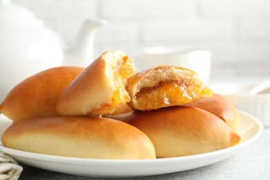 Photo of Tasty baked patties with orange jam on light grey table, closeup
