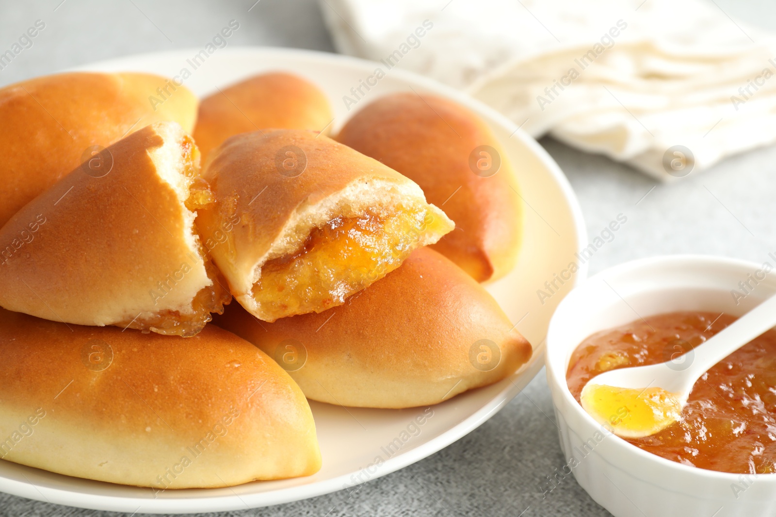 Tasty baked patties with orange jam on light grey table, closeup Photo of Tasty baked patties with orange jam on light grey table, closeup