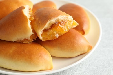 Photo of Tasty baked patties with orange jam on light grey table, closeup