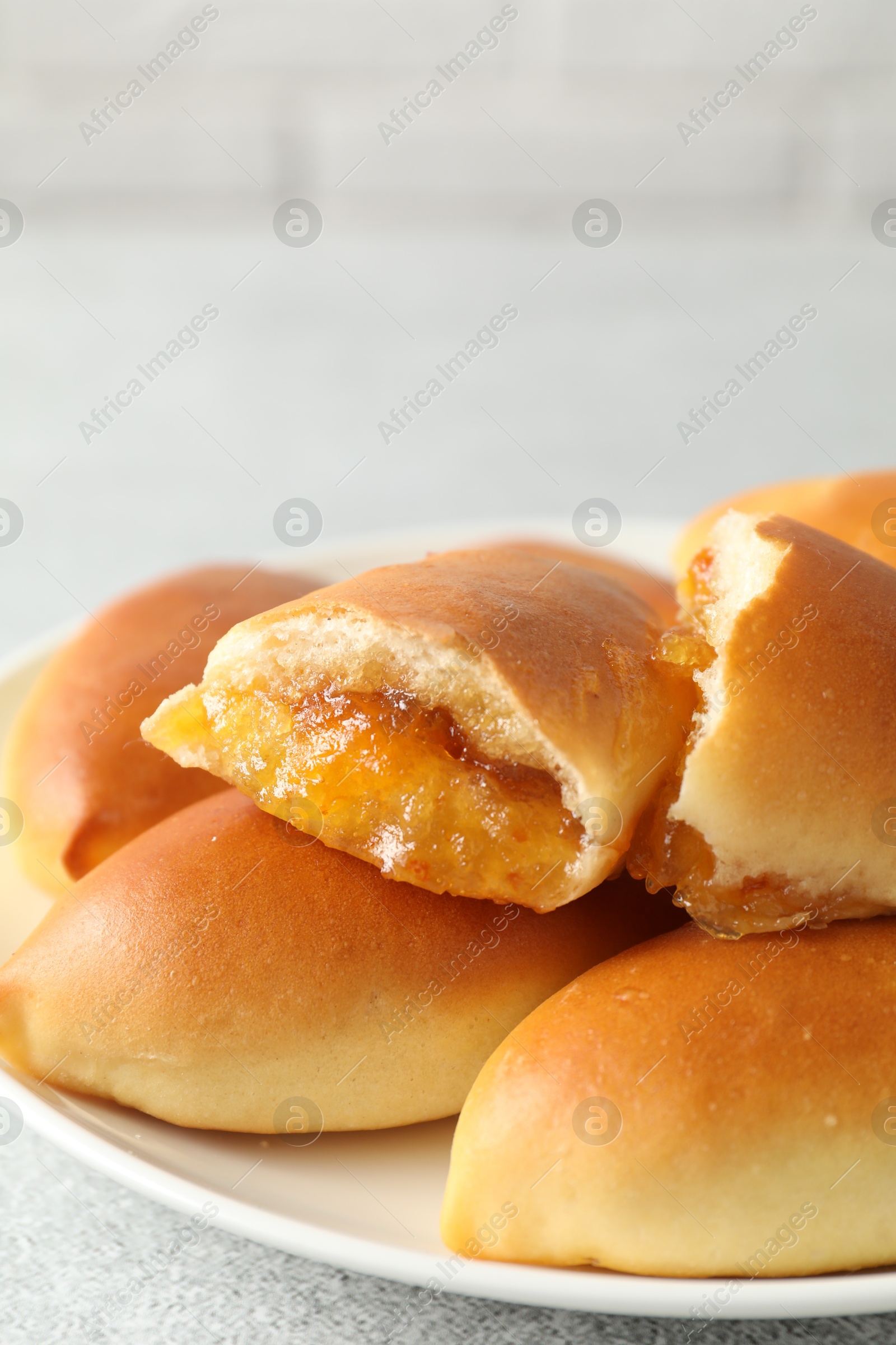 Tasty baked patties with orange jam on light grey table, closeup Photo of Tasty baked patties with orange jam on light grey table, closeup