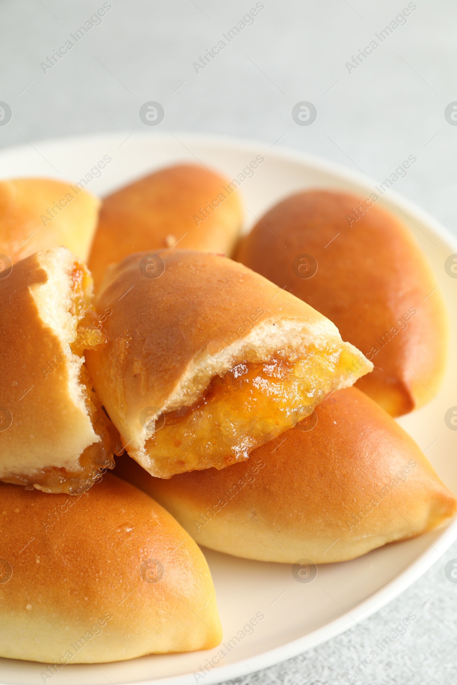 Tasty baked patties with orange jam on light grey table, closeup Photo of Tasty baked patties with orange jam on light grey table, closeup