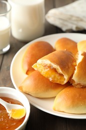 Photo of Tasty baked patties with orange jam on wooden table, closeup