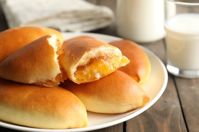 Photo of Tasty baked patties with orange jam on wooden table, closeup