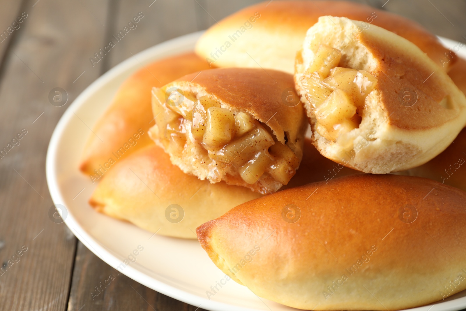Tasty baked patties with apples on wooden table, closeup Photo of Tasty baked patties with apples on wooden table, closeup