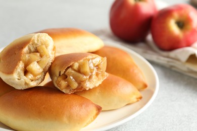Photo of Tasty baked patties with apples on light grey table, closeup