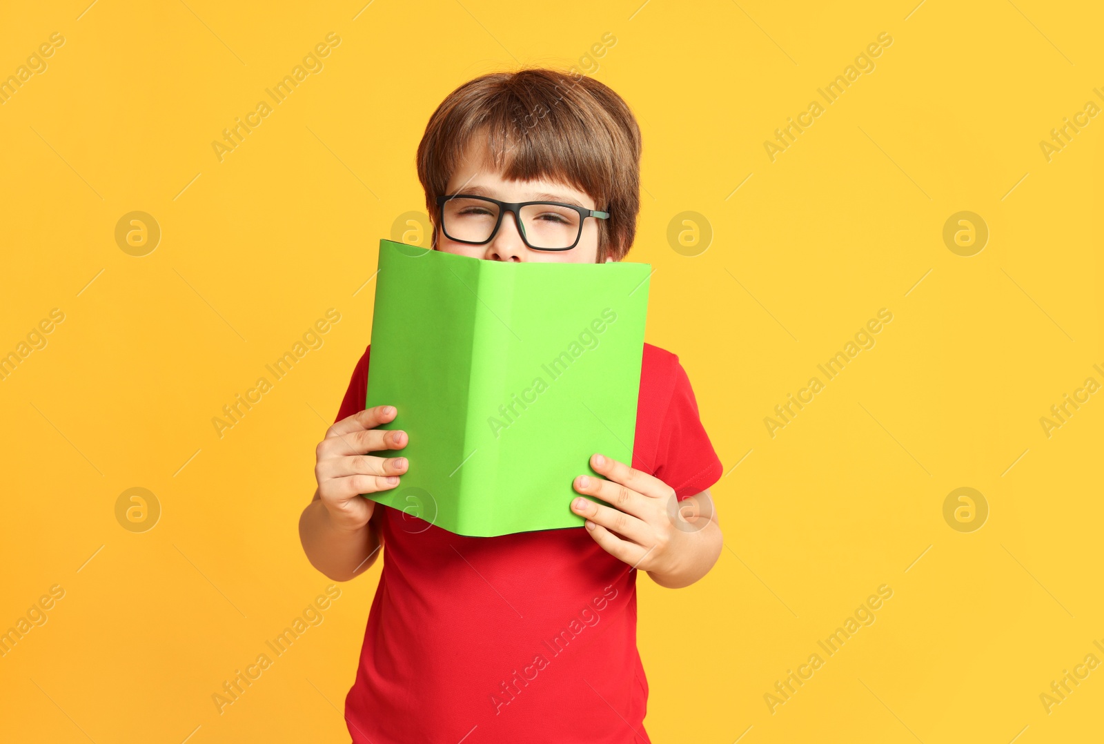 Little boy with book on orange background Photo of Little boy with book on orange background