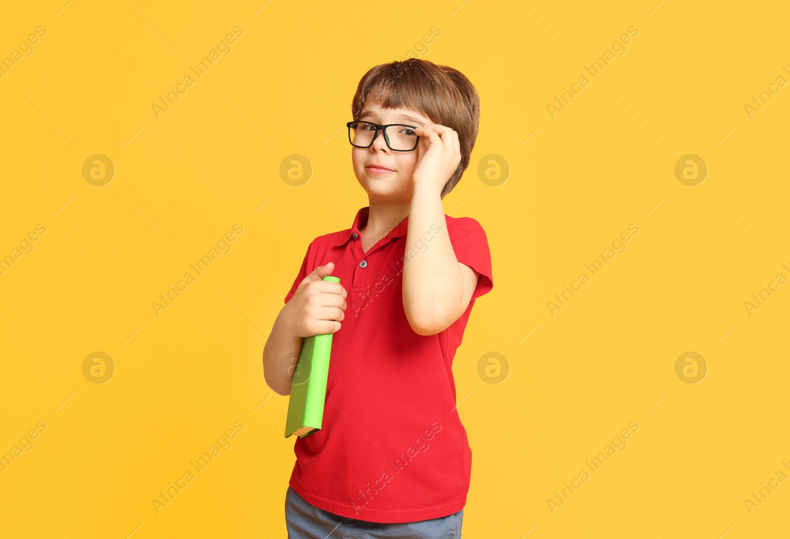 Little boy with book on orange background Photo of Little boy with book on orange background