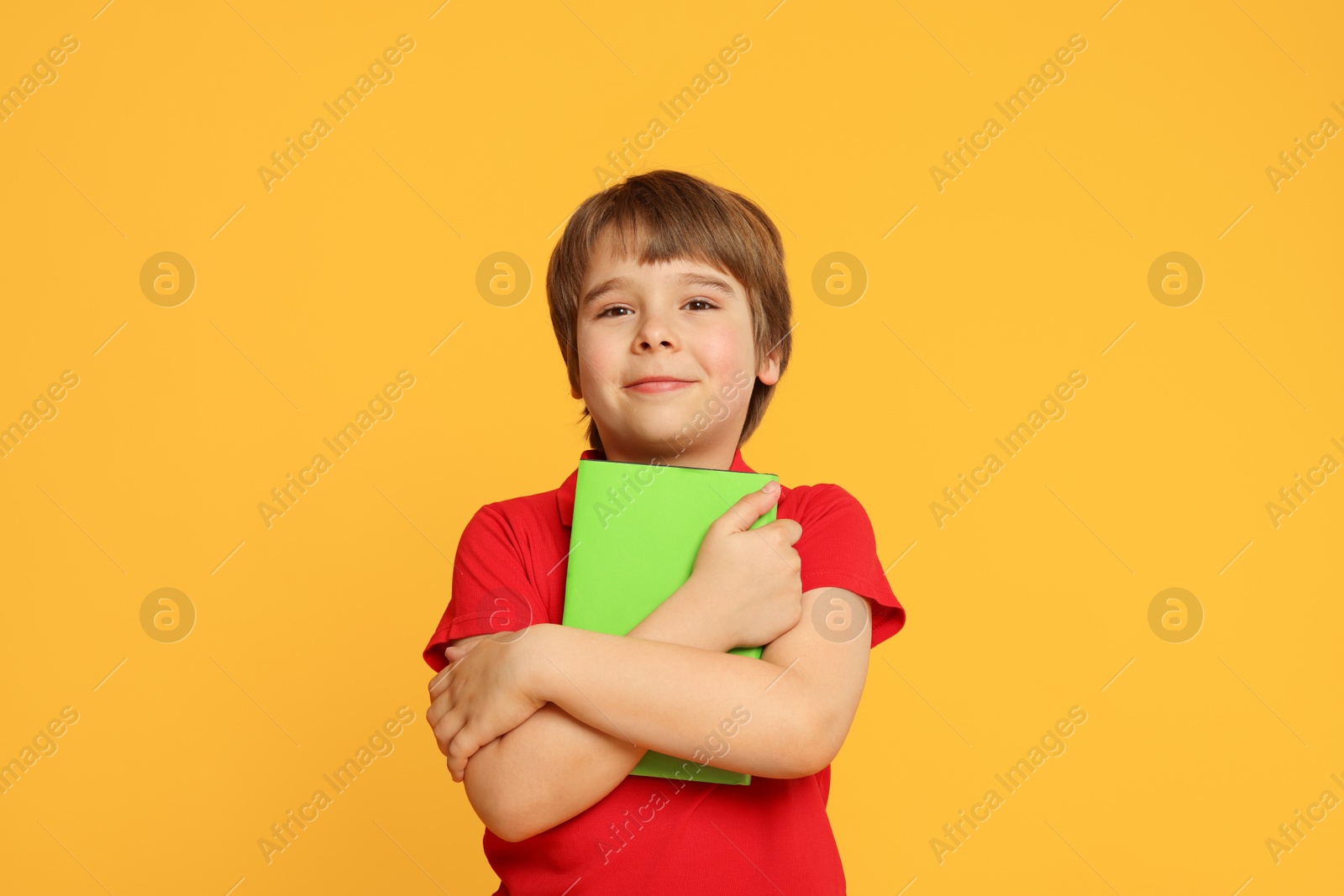 Little boy with book on orange background Photo of Little boy with book on orange background