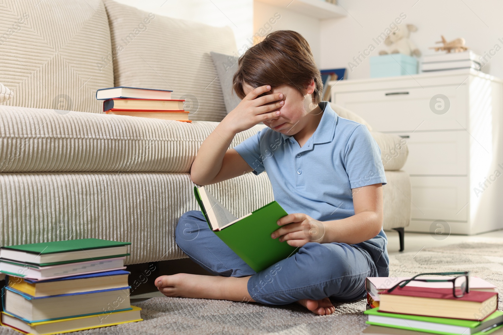 Upset boy struggling with reading books at home Photo of Upset boy struggling with reading books at home