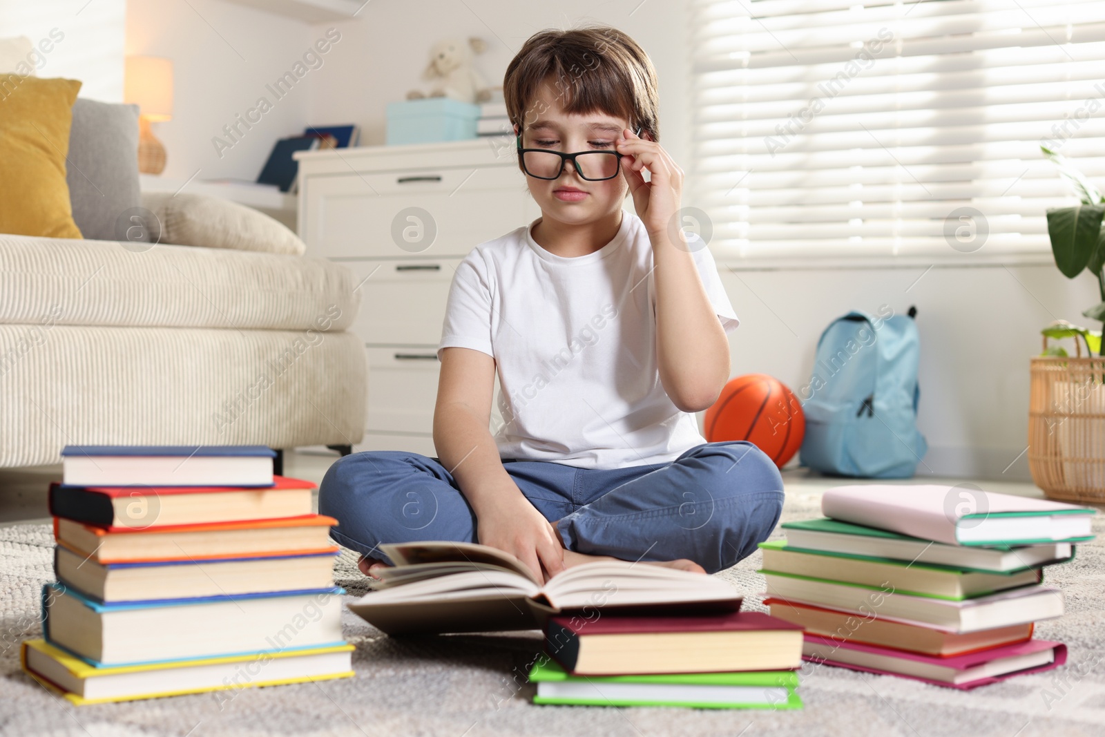 Boy with many different books on floor at home Photo of Boy with many different books on floor at home