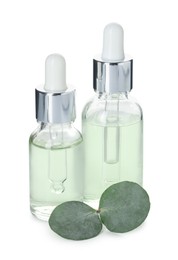 Photo of Bottles of essential oil and eucalyptus leaves isolated on white