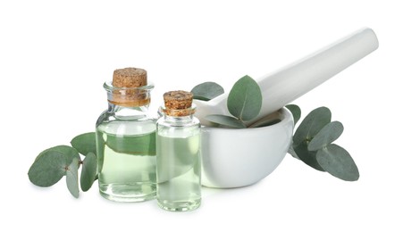 Photo of Bottles of essential oil, eucalyptus leaves, mortar and pestle isolated on white