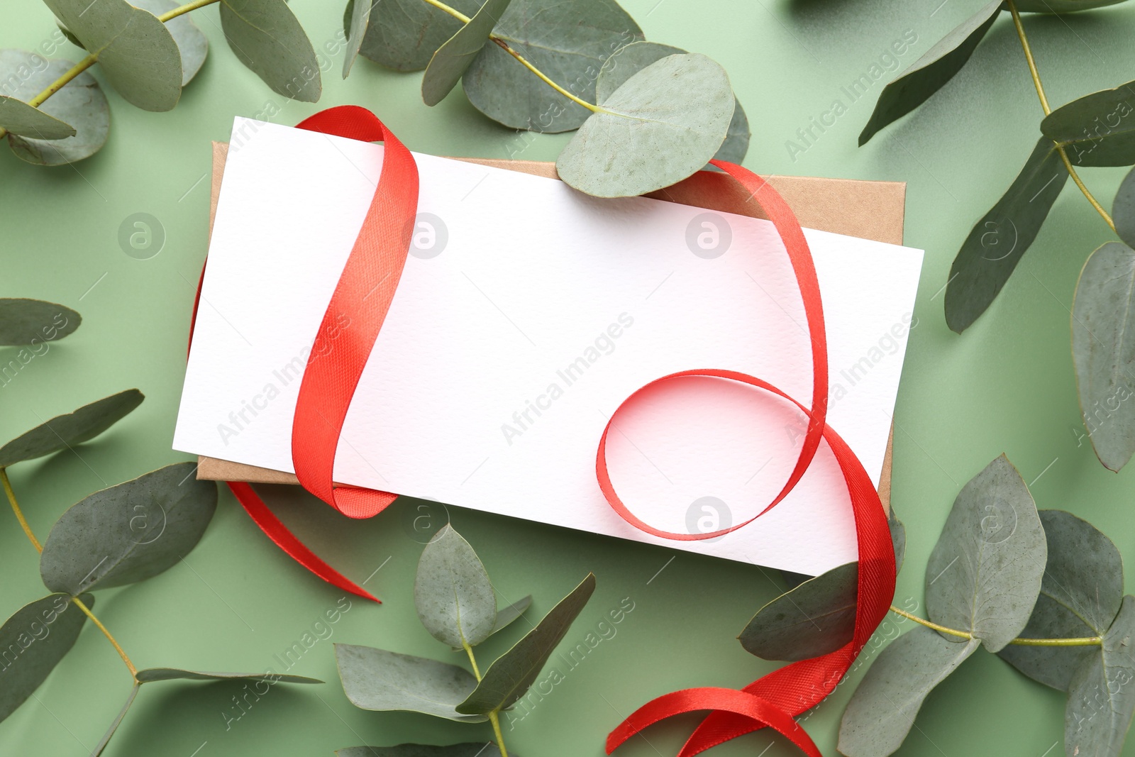 Blank card, ribbon and eucalyptus branches on light green background, flat lay Photo of Blank card, ribbon and eucalyptus branches on light green background, flat lay