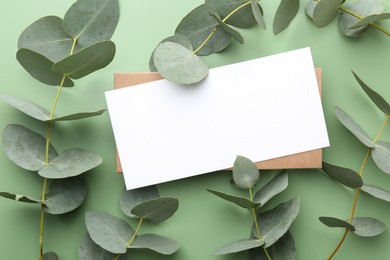 Photo of Blank card and eucalyptus branches on light green background, flat lay