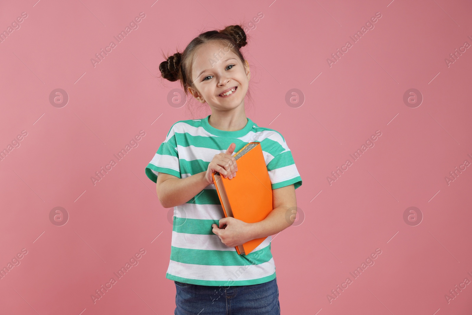 Cute girl with book on pink background Photo of Cute girl with book on pink background