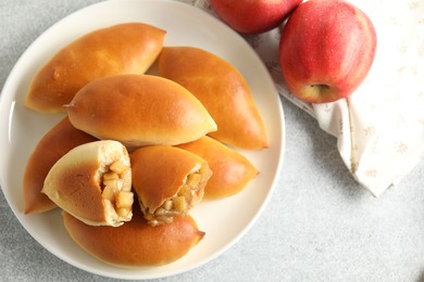 Photo of Tasty baked patties with apples on light grey table, flat lay